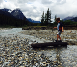 Child crossing stream on log