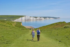 Retired couple walking toward the sea in Eastbourne on sunny day