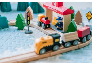 Cute toy train set with wooden rails, trees, a station, signage and conductor