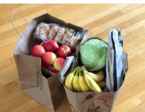 Two paper bags full of groceries on a hard wood floor