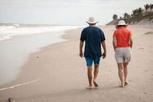 Picture of a retired couple walking on the beach.